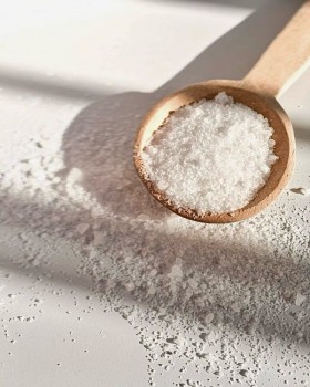 Plate with pink kosher salt, wooden spoon, and dried herbs with overlaid Melach Kosher Salt logo tex
