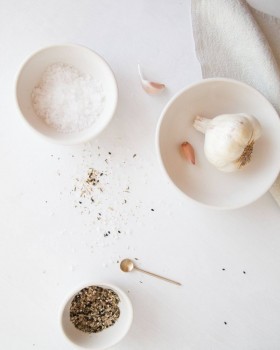 Plate with pink kosher salt, wooden spoon, and dried herbs with overlaid Melach Kosher Salt logo tex